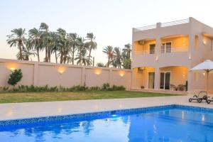 a villa with a swimming pool in front of a house at Royal Nile Villas - Nile View Apartment 1 in Luxor