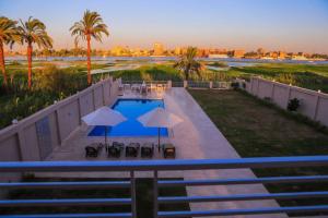 ルクソールにあるRoyal Nile Villas - Nile View Apartment 1のパラソルと椅子付きのプールの景色を望めます。
