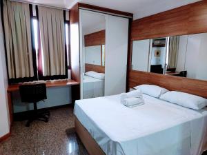 a bedroom with a bed and a desk and a mirror at Apart Hotel Life Resort - Beira Lago N D15 in Brasília