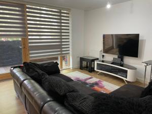 sala de estar con sofá de cuero y TV de pantalla plana en Spacious 2 Bedroom Modern Flat, en Londres