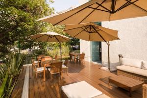 una terraza de madera con mesas, sillas y sombrillas en Hampton by Hilton Guadalajara Expo, en Guadalajara