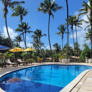 uma piscina no resort com palmeiras ao fundo em Porto do Sol - Chalé 07 em Pipa