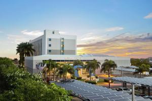 Hilton DoubleTree by Hilton Managua في ماناغوا: مبنى ابيض كبير امامه نخيل