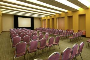 una sala de conferencias con sillas rosas y una pantalla en Hilton Garden Inn Monterrey Airport, en Monterrey