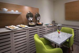 a dining room with a table and green chairs at Hilton Garden Inn Monterrey Airport in Monterrey