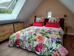 a bedroom with a bed with a floral bedspread and red pillows at Ferienwohnungen am Wasserfall in Bad Urach