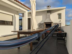 een hangmat op een patio met een tafel en een open haard bij Small house with private park and yard in Terrugem