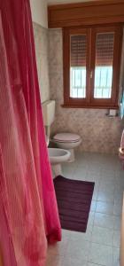 a bathroom with a toilet and a pink shower curtain at Casa Nostra in Imola