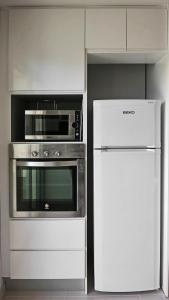 a white kitchen with a microwave and a refrigerator at Apartment Escorpiones in Torrevieja