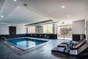 a large swimming pool with two chairs and a table at DoubleTree by Hilton Queretaro in Querétaro