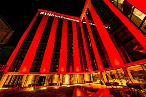 ein großes Gebäude mit einer rot beleuchteten Fassade in der Unterkunft Hilton Garden Inn Santiago Del Estero - 4 Estrellas in Santiago del Estero
