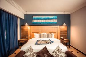 1 dormitorio con 1 cama blanca grande y paredes azules en Marcsons Hotels and Resorts, en Limbe