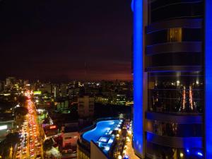 Embassy Suites by Hilton Santo Domingo في سانتو دومينغو: اطلالة على مدينة في الليل مع مبنى