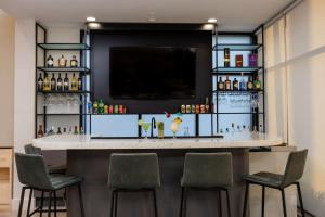 a bar in a room with chairs and a tv at Hampton By Hilton San Jose Airport Costa Rica in Alajuela