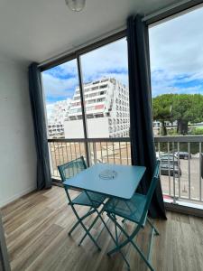 a blue table and chairs in a room with a large window at Les Appartements De Lina By LG Immo - Self Check-In - in La Grande-Motte