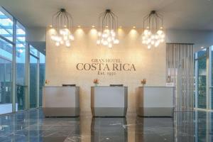 a lobby with chandeliers and a sign on the wall at Gran Hotel Costa Rica, Curio Collection By Hilton in San José