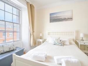 a white bedroom with a large bed and a window at Sublyme in Lyme Regis