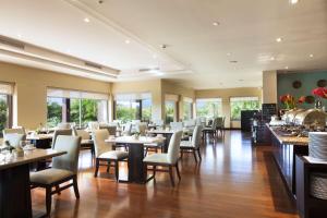 a dining room with tables and chairs and windows at Hilton Garden Inn Guanacaste Airport in Liberia