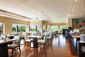- une salle à manger avec des tables, des chaises et des fenêtres dans l'établissement Hilton Garden Inn Guanacaste Airport, à Liberia