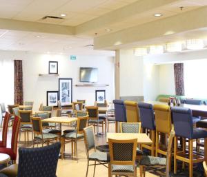 comedor con sillas, mesas y TV en Hampton by Hilton Saltillo Zona Aeropuerto, en Saltillo