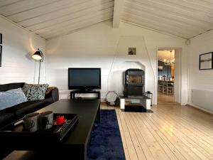 a living room with a couch and a flat screen tv at Rustic cabin on Lake Sjusjøen with a lovely view in Ringsaker