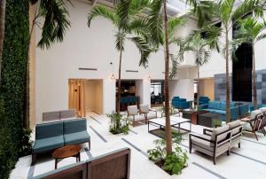 een lobby met palmbomen en blauwe stoelen bij DoubleTree by Hilton Veracruz in Veracruz