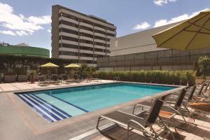 a large swimming pool with chairs and an umbrella at Hilton Colon Quito Hotel in Quito