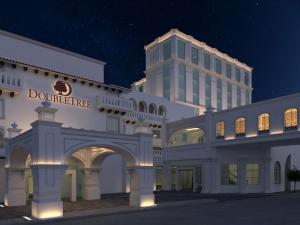 a large white building with a tall building in the background at Doubletree By Hilton Toluca in Toluca