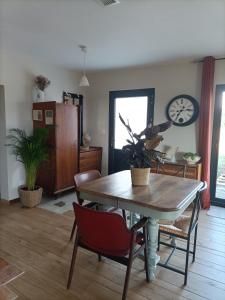 ein Esszimmer mit einem Tisch, Stühlen und einer Uhr in der Unterkunft La Grange des Anges in Blanc