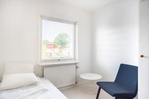 1 dormitorio con cama, silla azul y ventana en By The Bay room in a shared villa en Gotemburgo