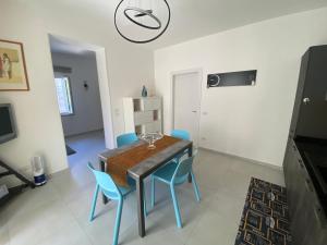 a dining room with a table and blue chairs at AleVale apartment 450mt mare in Grottammare