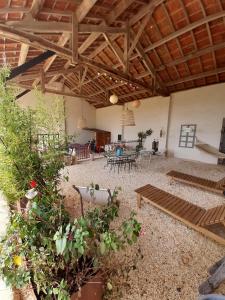 eine große Terrasse mit Tischen, Stühlen und Pflanzen in der Unterkunft La Grange des Anges in Blanc