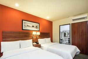 two beds in a hotel room with orange walls at Hampton by Hilton San Juan del Rio in San Juan del Río