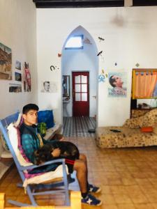 mężczyzna siedzący na krześle w salonie z psem w obiekcie La Casa del Cine en Níjar w mieście Níjar