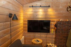 a living room with a television on a wooden wall at Torbjørnhytta in Haugen