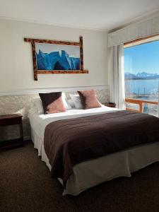 ein Schlafzimmer mit einem großen Bett mit einem großen Fenster in der Unterkunft Darwin Hotel in Puerto Natales