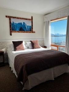 ein Schlafzimmer mit einem großen Bett und einem großen Fenster in der Unterkunft Darwin Hotel in Puerto Natales