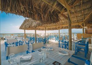 a restaurant with blue chairs and tables on the beach at Mangrove Beach Corendon Curacao All-Inclusive Resort, Curio in Willemstad