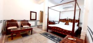 a bedroom with a canopy bed and two chairs at Hotel MSD Niwas in Mandāwa