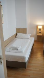 una camera da letto con un letto con lenzuola bianche e un pavimento in legno di Hotel Hafner a Stoccarda
