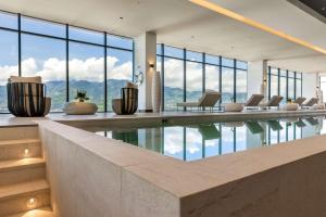 Habitación con piscina con sillas y ventanas. en Hilton San Jose La Sabana, en San José