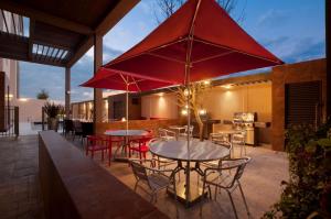 a patio with tables and chairs and red umbrellas at Homewood Suites by Hilton Queretaro in Querétaro
