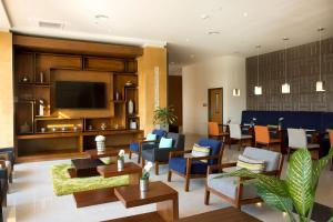 a hotel lobby with chairs and tables and a television at Hampton Inn & Suites by Hilton Paraiso in Paraíso