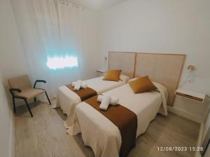 een hotelkamer met 2 bedden en een stoel bij RosaHome Sanxenxo in Sanxenxo