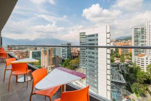 balcón con mesas y sillas y vistas a la ciudad en Hampton by Hilton Medellin, en Medellín
