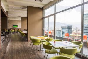 a restaurant with tables and chairs and large windows at Hampton by Hilton Medellin in Medellín