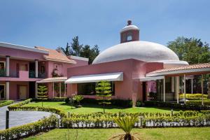ein rosafarbenes Haus mit einer weißen Kuppel darüber in der Unterkunft Hilton MM Grand Hotel Puebla, Tapestry Collection in Puebla