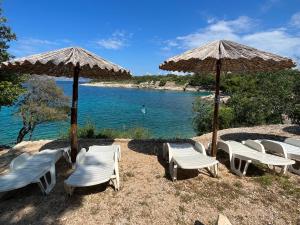 a group of chairs and umbrellas next to the water at Pinezići apartman Niccole in Pinezici