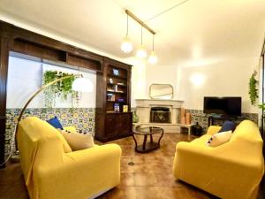 a living room with two yellow chairs and a fireplace at Yucca House Carcavelos Beach in Carcavelos