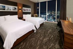 a hotel room with two beds and a window at Hilton Garden Inn Monterrey Obispado in Monterrey
